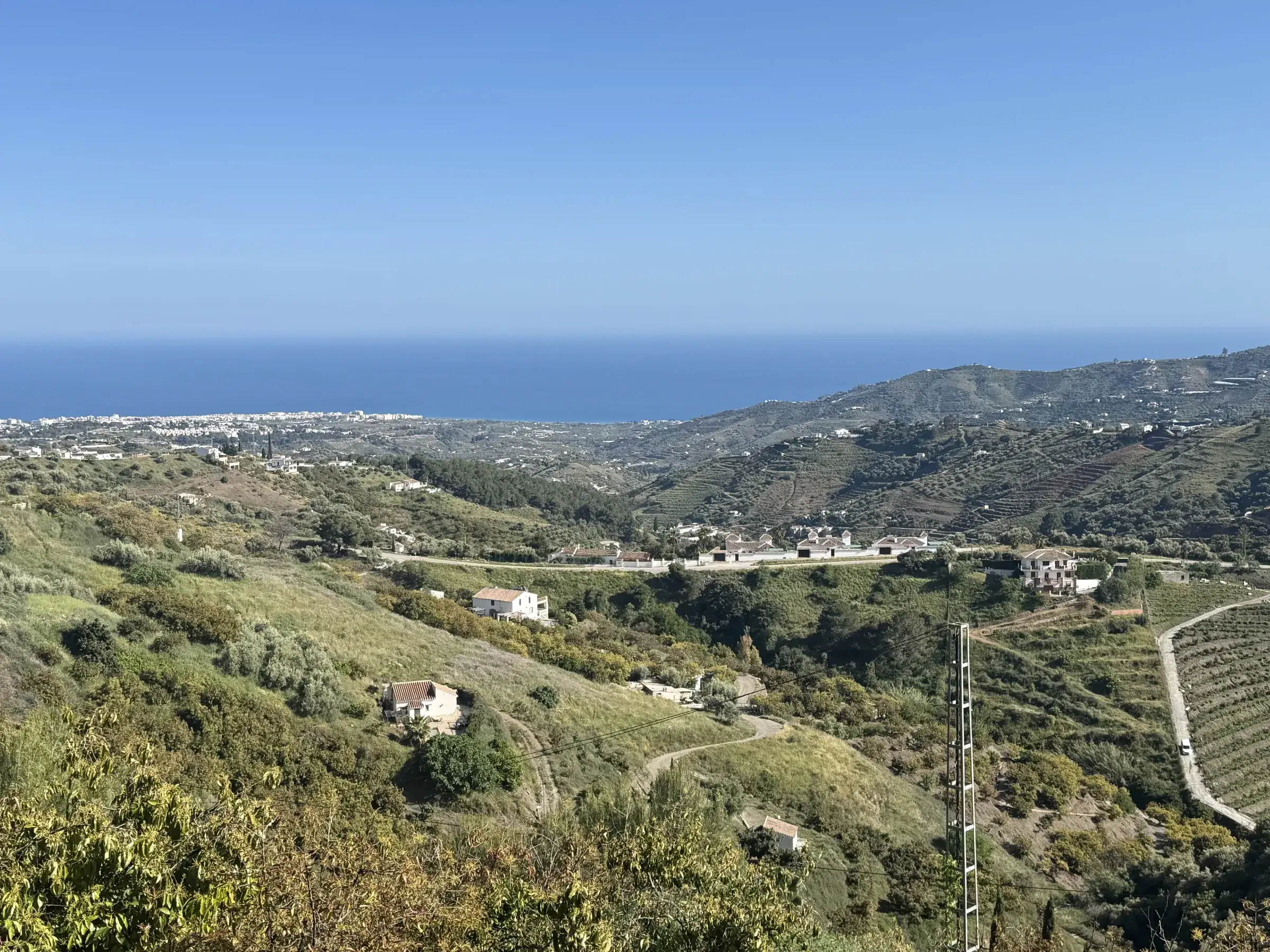 View from above Frigiliana down the Axarquía valley to the Mediterranean Sea, terraced hillsides and white villages along the coast.