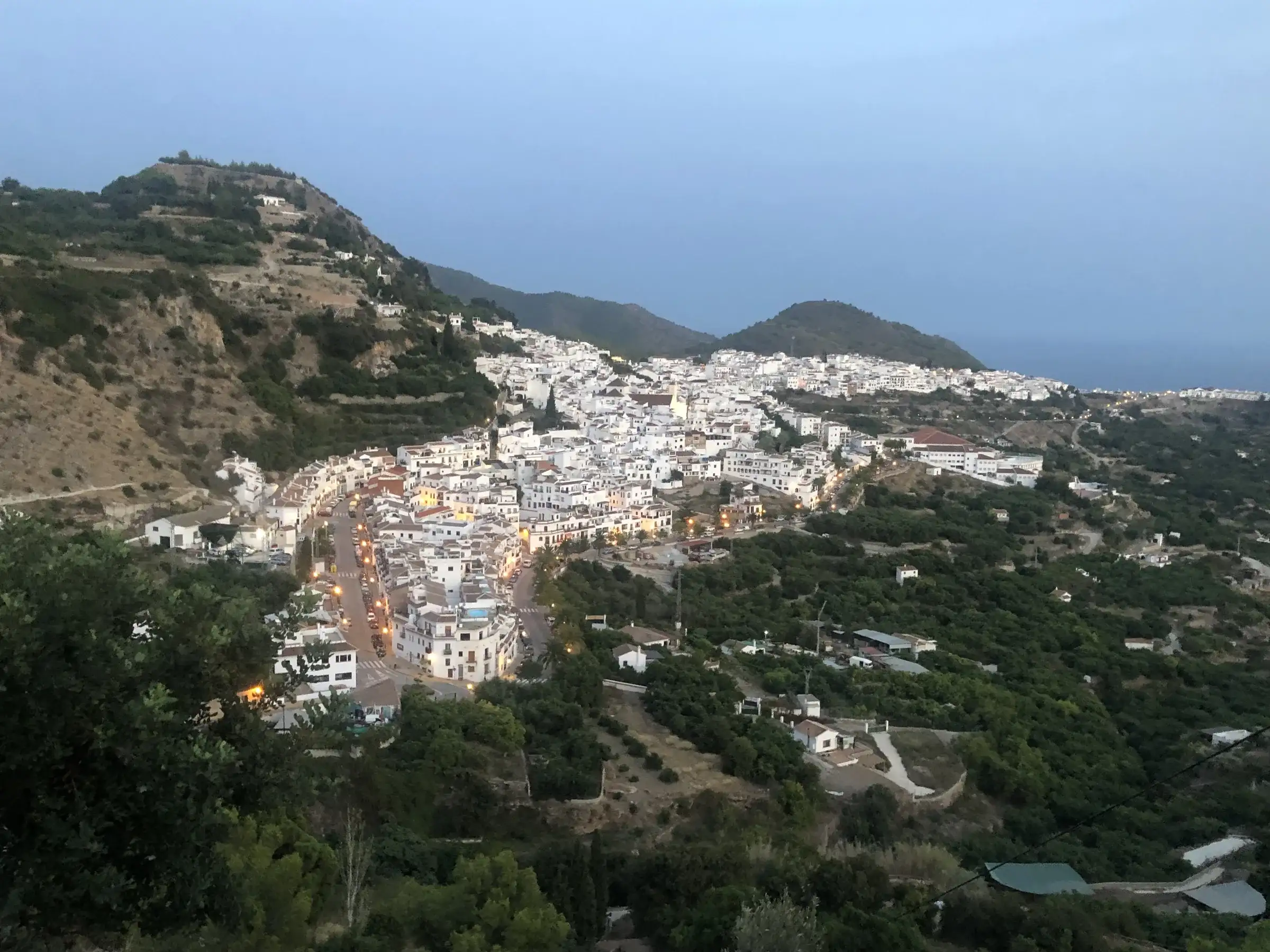 Frigiliana white village at dusk, lit streets winding up the hillside in Andalucia.