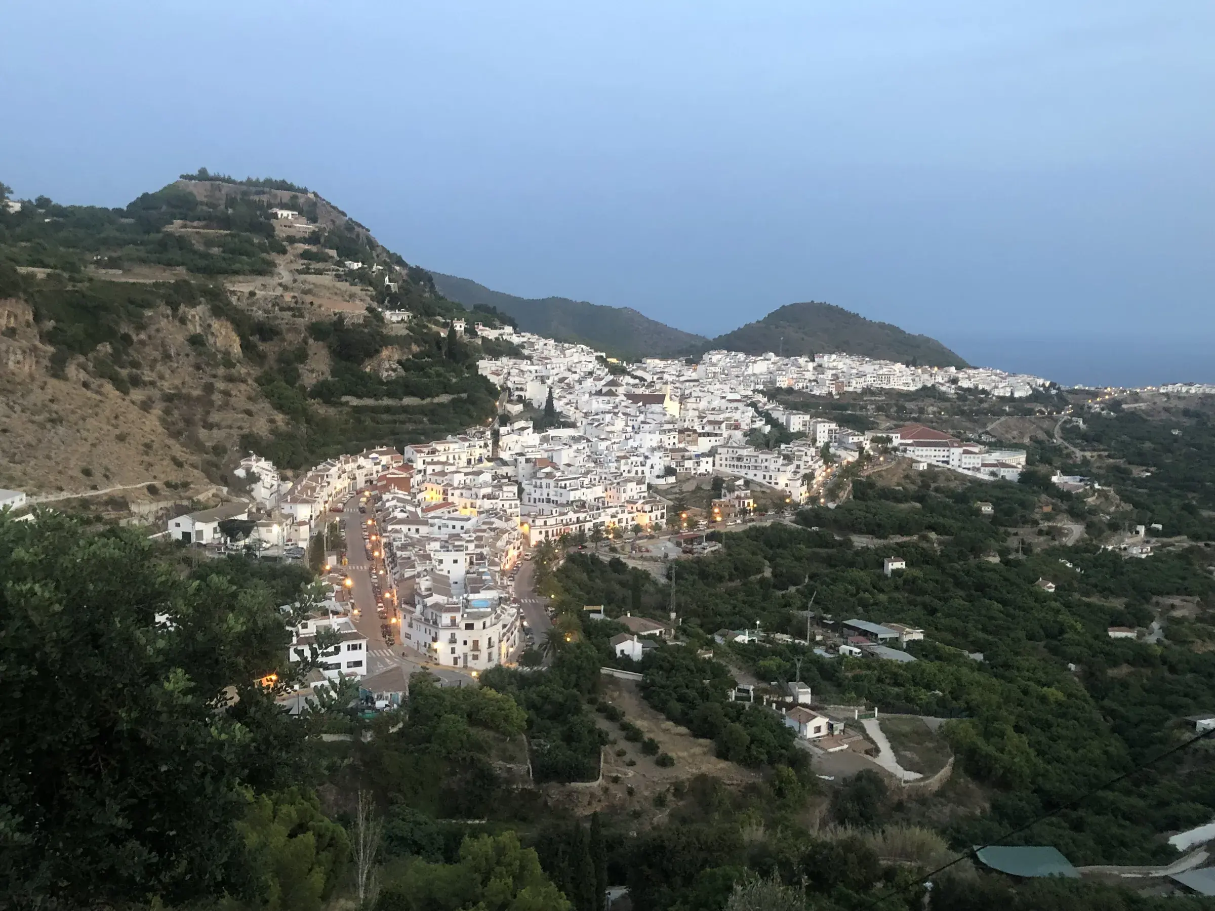 Frigiliana from above at twilight — the white village climbing the hillside, used as a filming location for Spanish films and TV series.