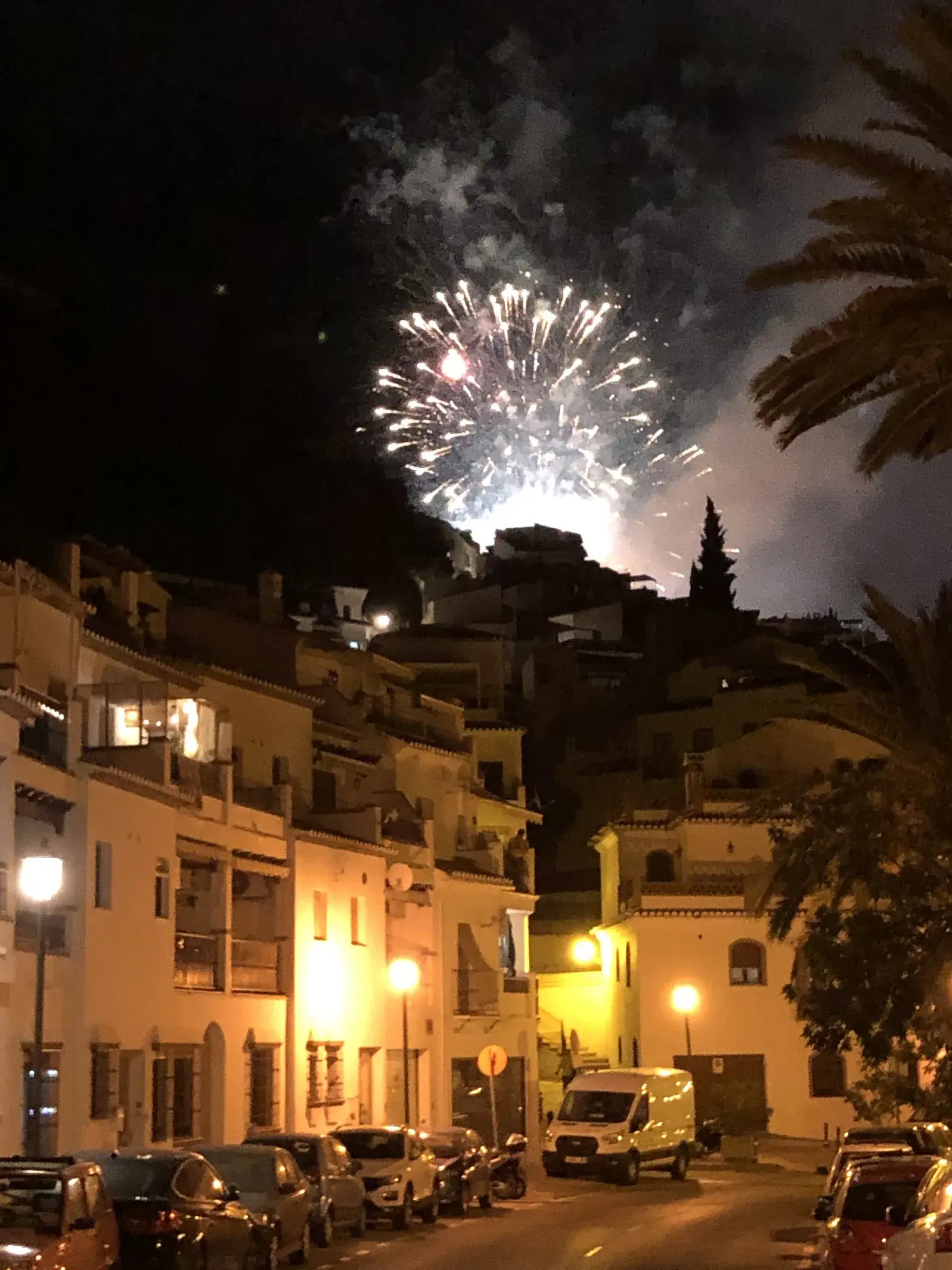 Pink fireworks bursting over Frigiliana's rooftops on a summer night.