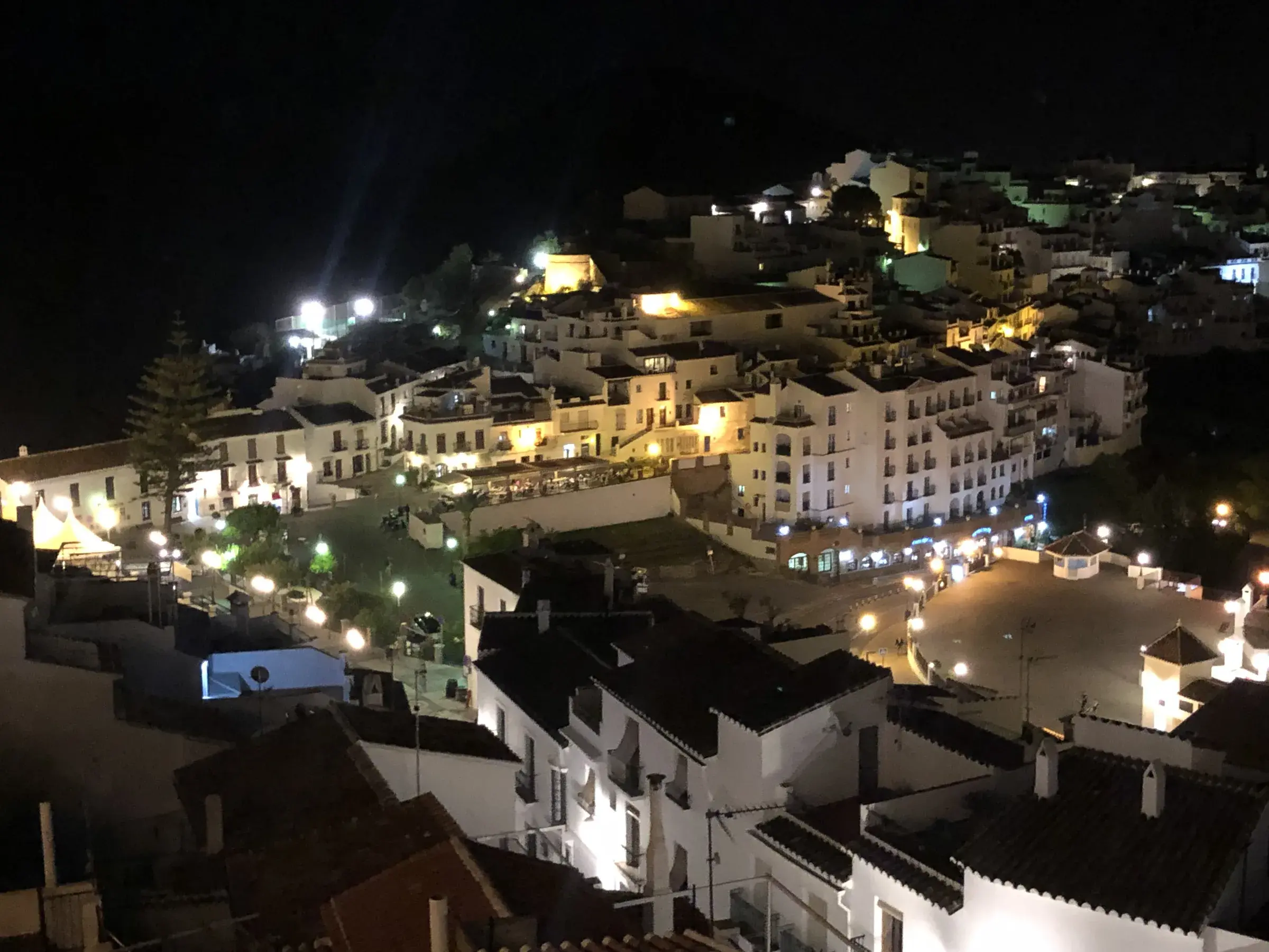 Frigiliana's whitewashed rooftops at night, warm lamplight in narrow lanes.
