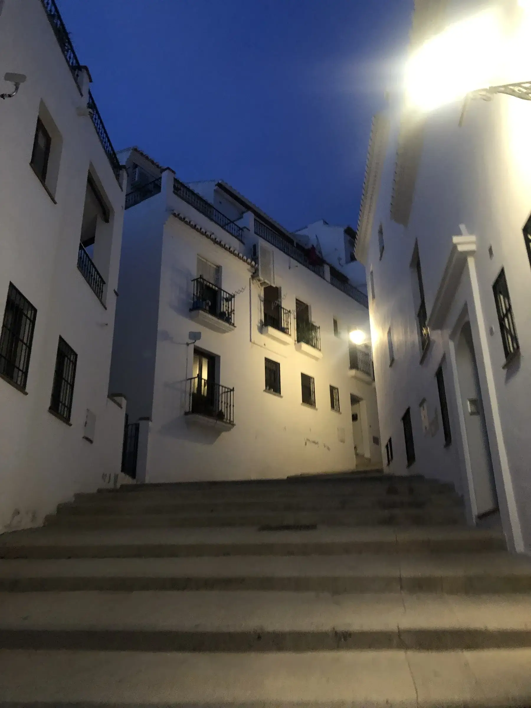 A whitewashed stepped alley in Frigiliana's old town at night — the kind of casco antiguo backdrop that has shown up in Spanish film and television for decades.